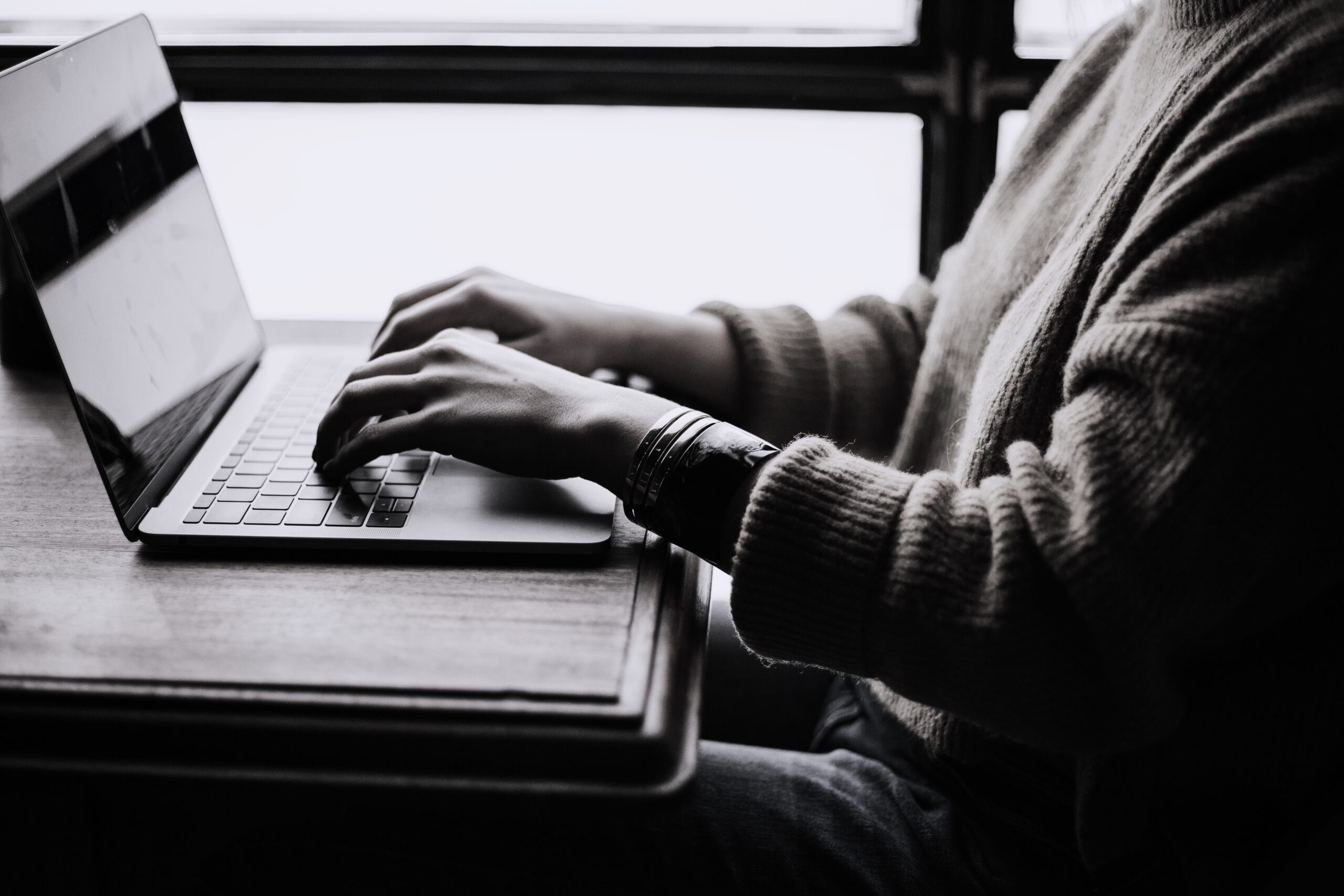 Hands typing on a laptop