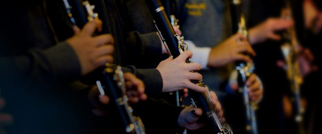 Students playing instruments in group music tuition lessons