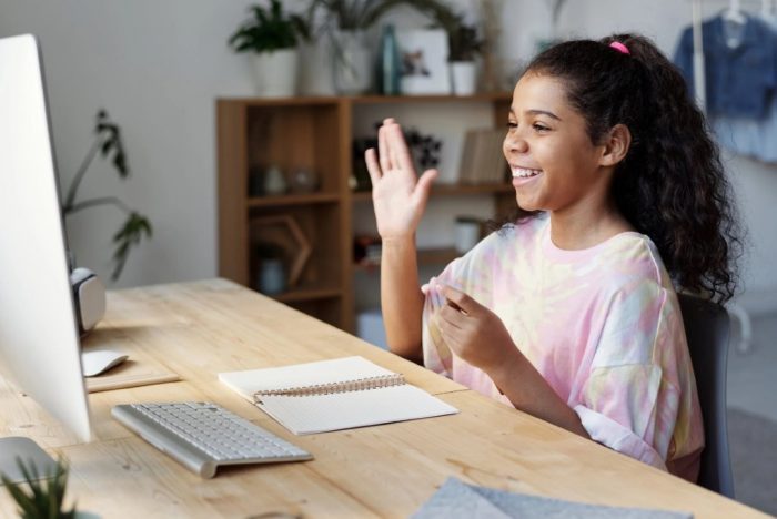 A girl waving at the camera at her online lesson, adapting to Covid-19, a potential customer from your online tuition business model