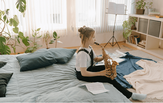 A person sitting on a bed playing a saxophone