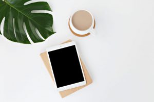 A tablet that has chosen installed software and a cup of tea with a plant.