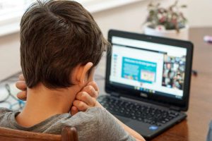 A young boy engaging with an online tuition business via laptop