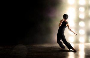 Male dances against backlighting with derby hat.